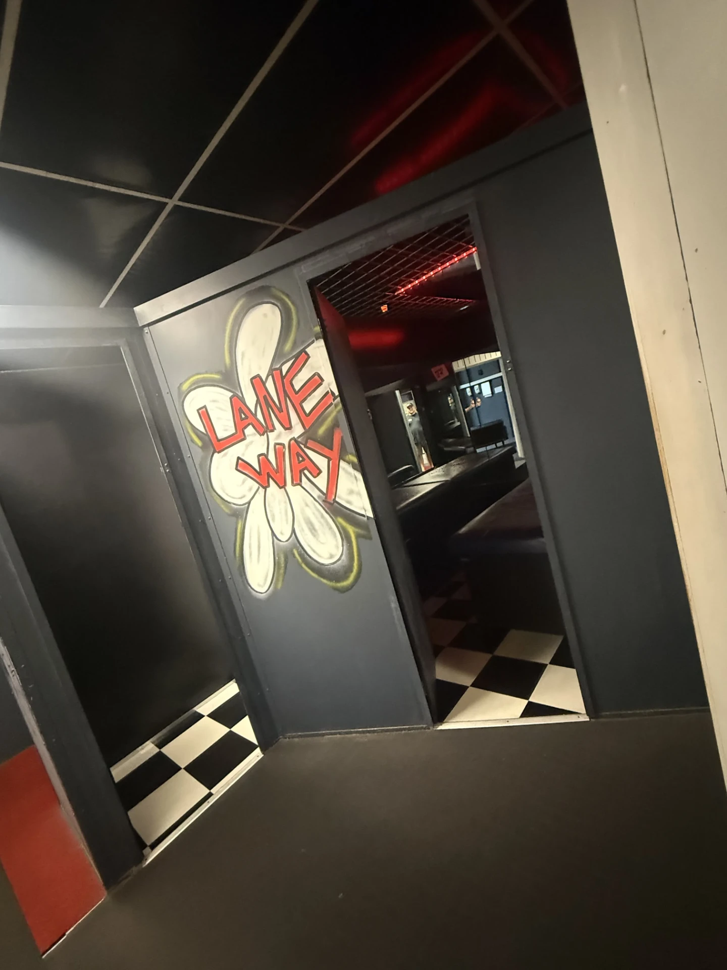 Interior walkway at Cruise Club Cairns leading through a painted doorway to a red-lit room with chequered flooring